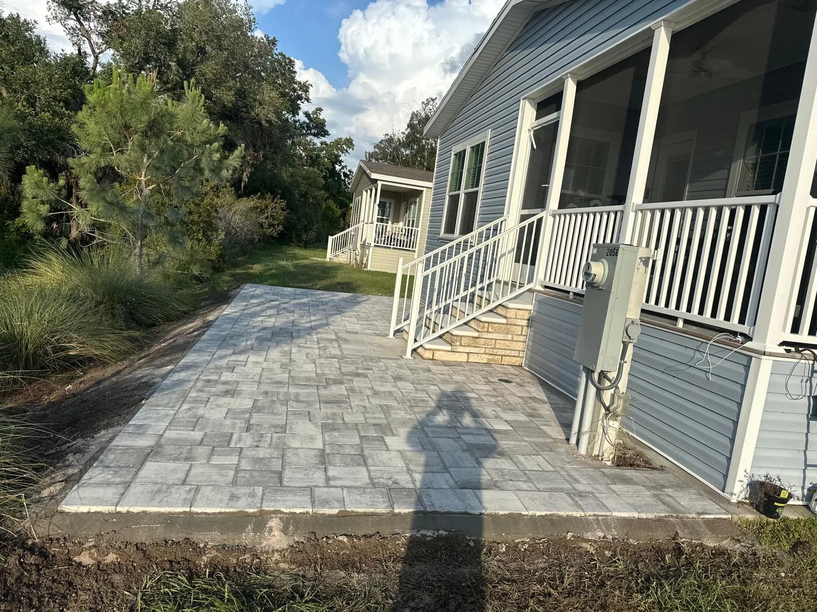 Gray paver patio installed beside a screened porch