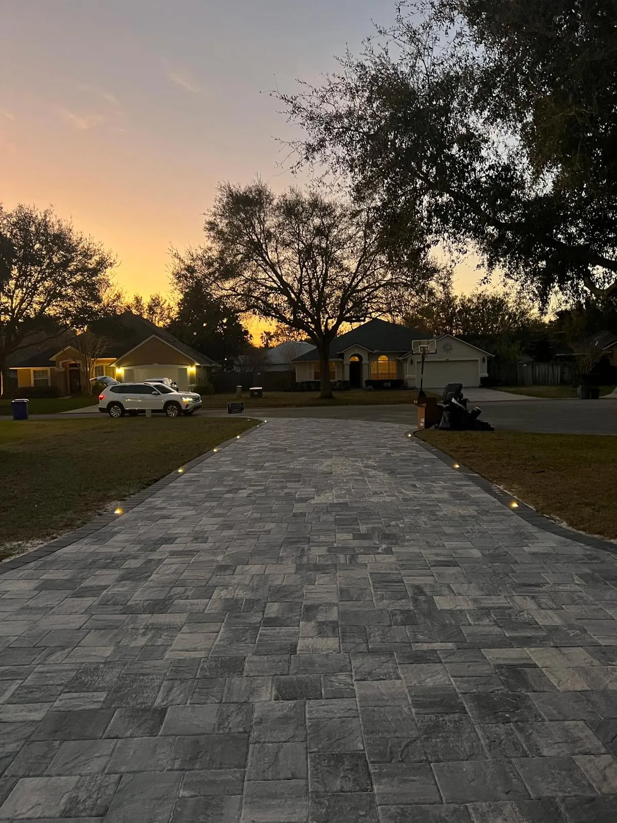 Paver driveway with recessed landscape lighting at dusk