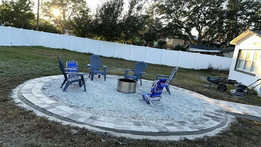Backyard fire pit with a paver border and Adirondack chairs